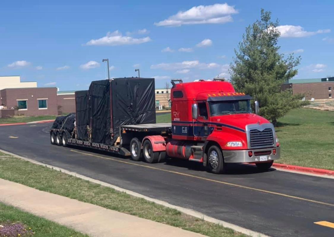 Red RY Mack truck with tarped load at industrial facility