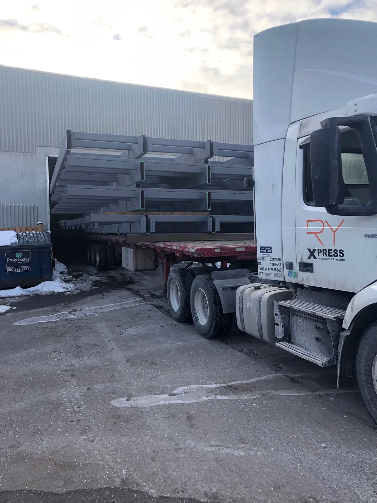 RyXpress branded truck loading steel beams at warehouse