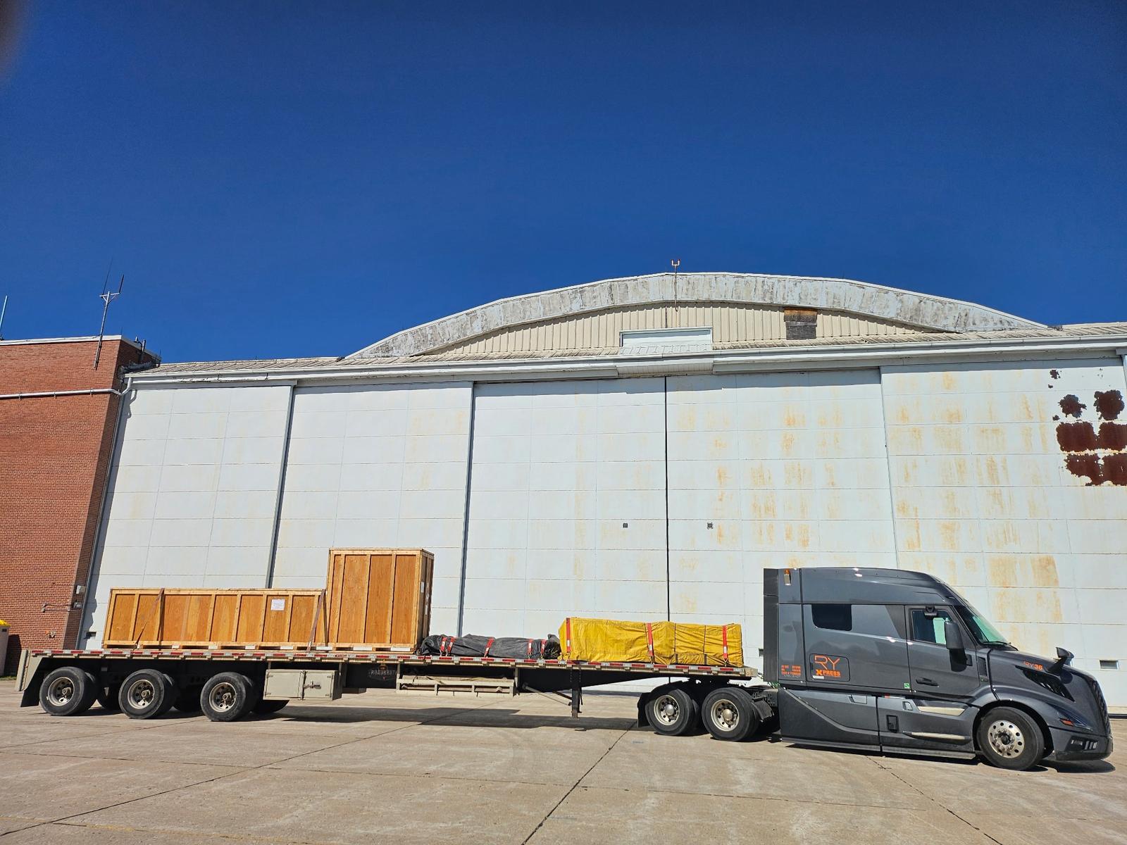 Gray RY Xpress Volvo VNL with crated cargo at warehouse facility
