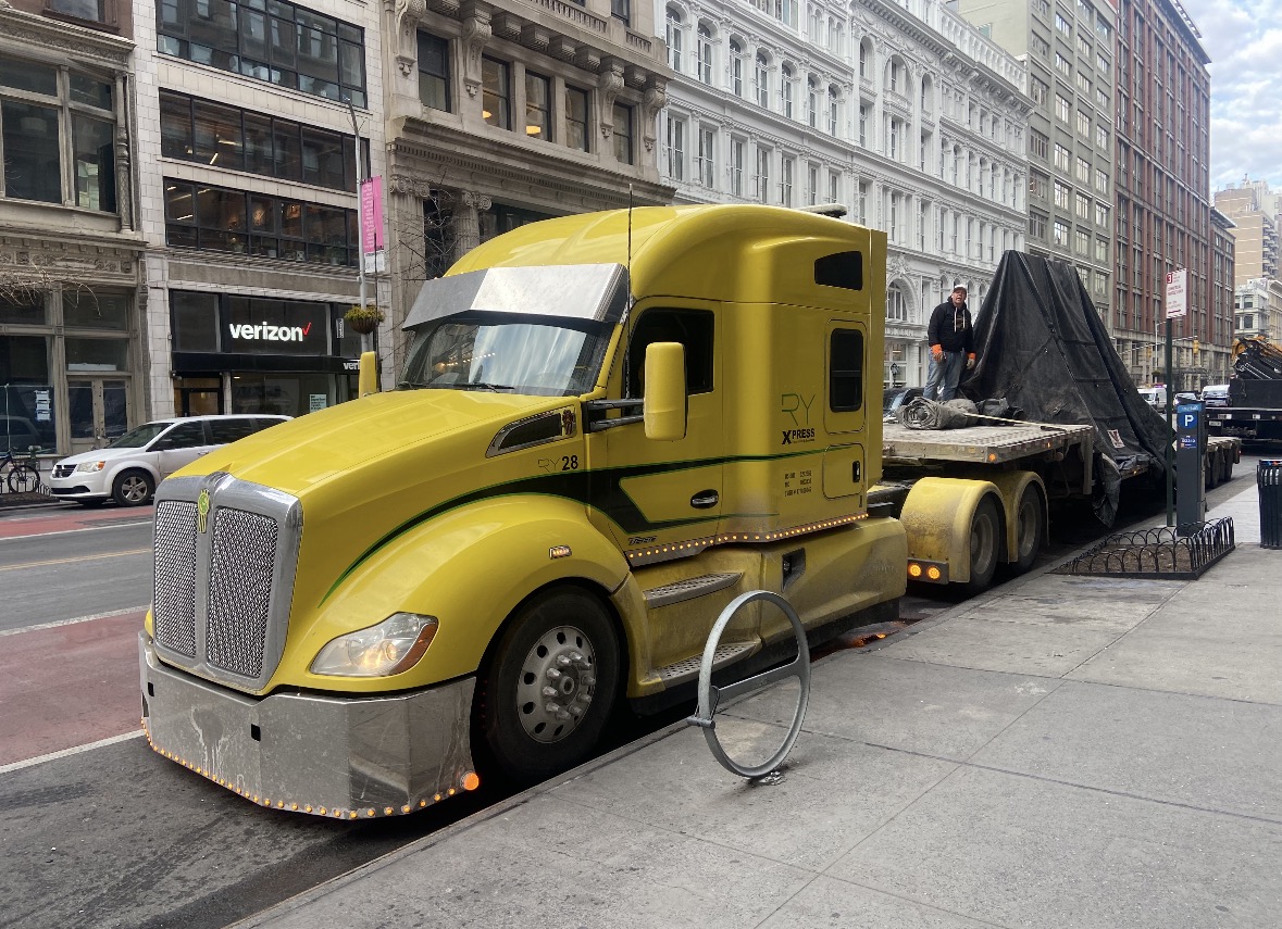 Yellow RY Kenworth T680 with worker on flatbed in NYC