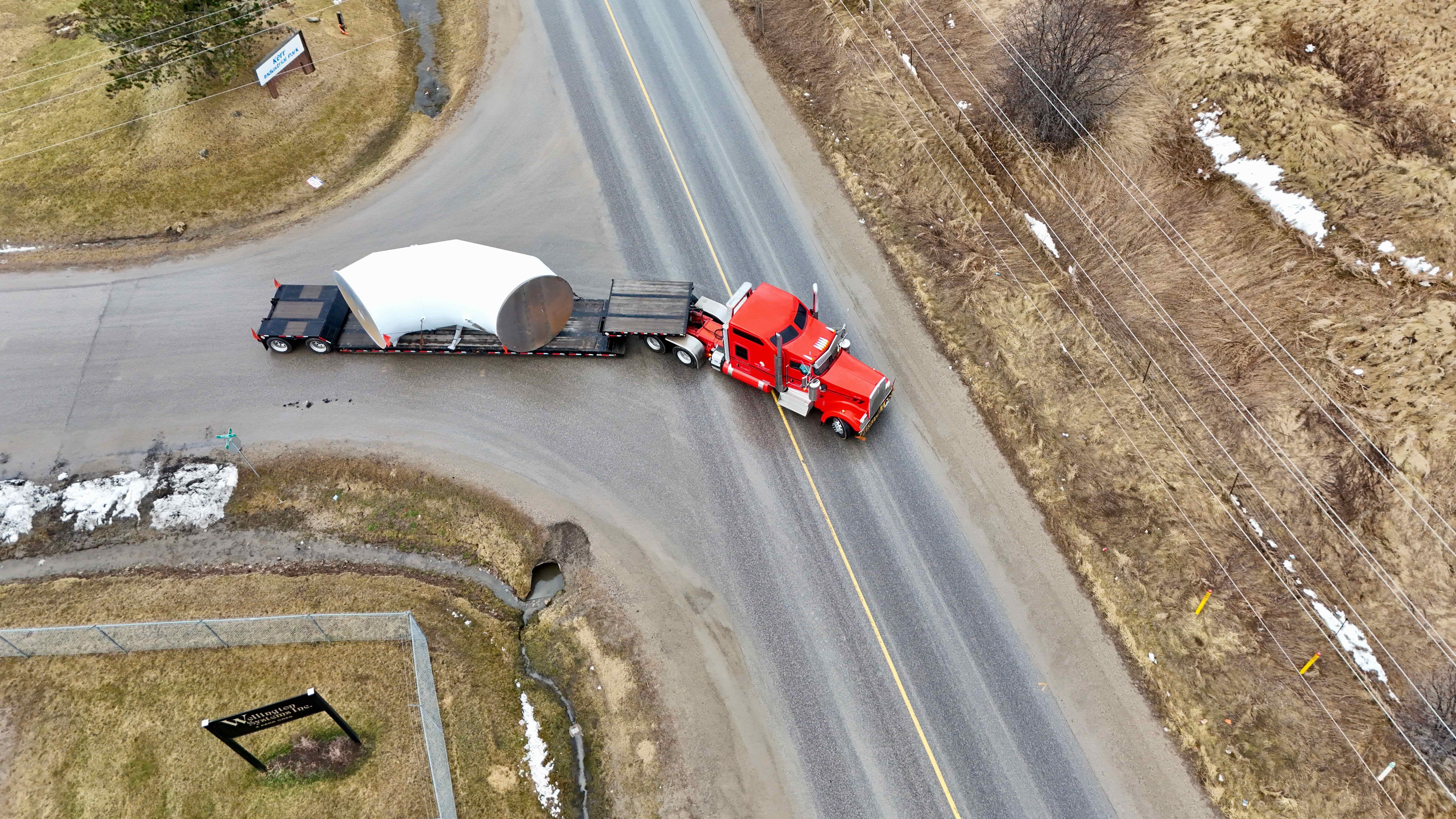 Aerial view of RY truck transporting large cylindrical vessel on rural highway