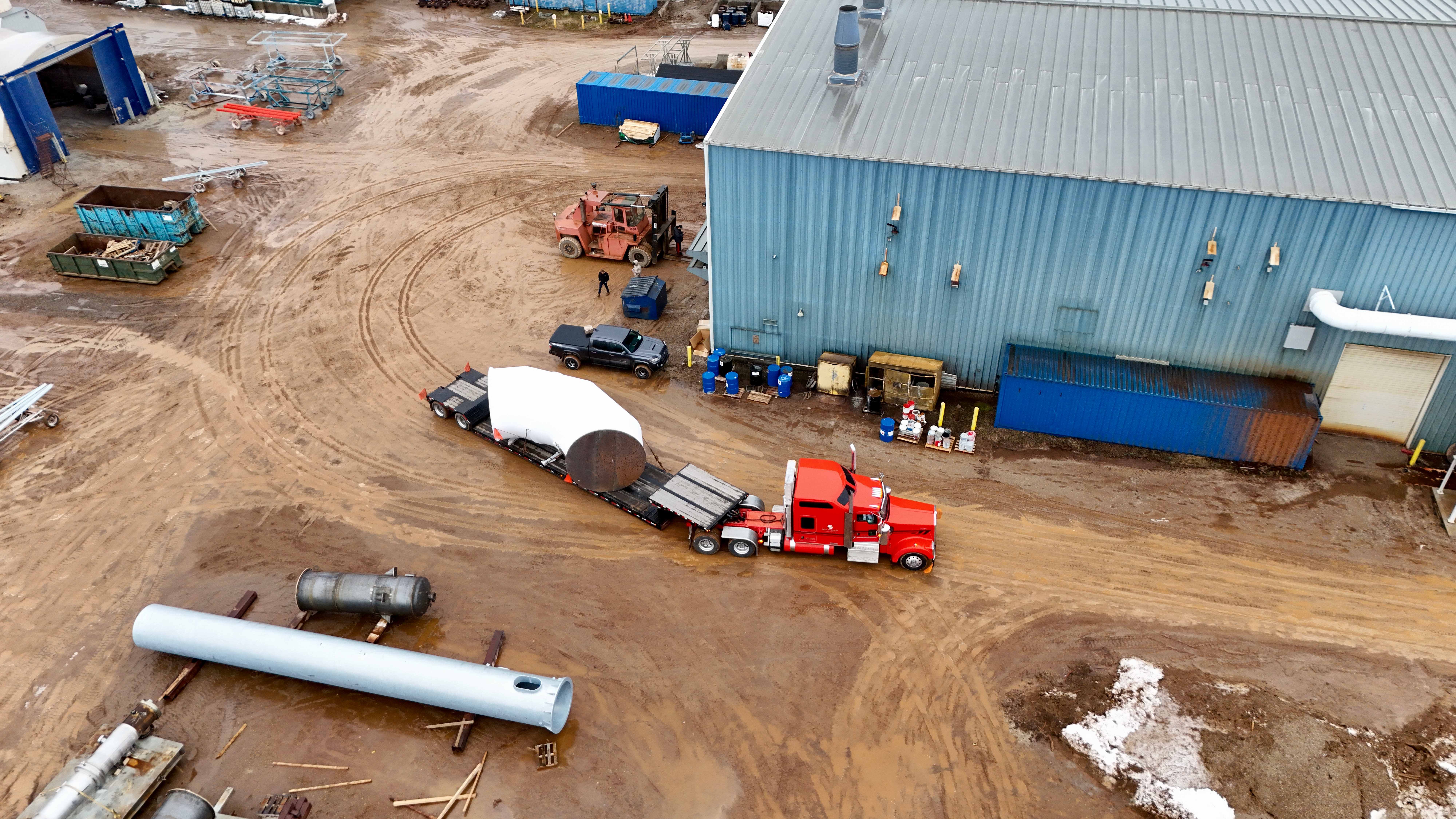 Aerial view of RY red truck loading oversized tank at industrial facility